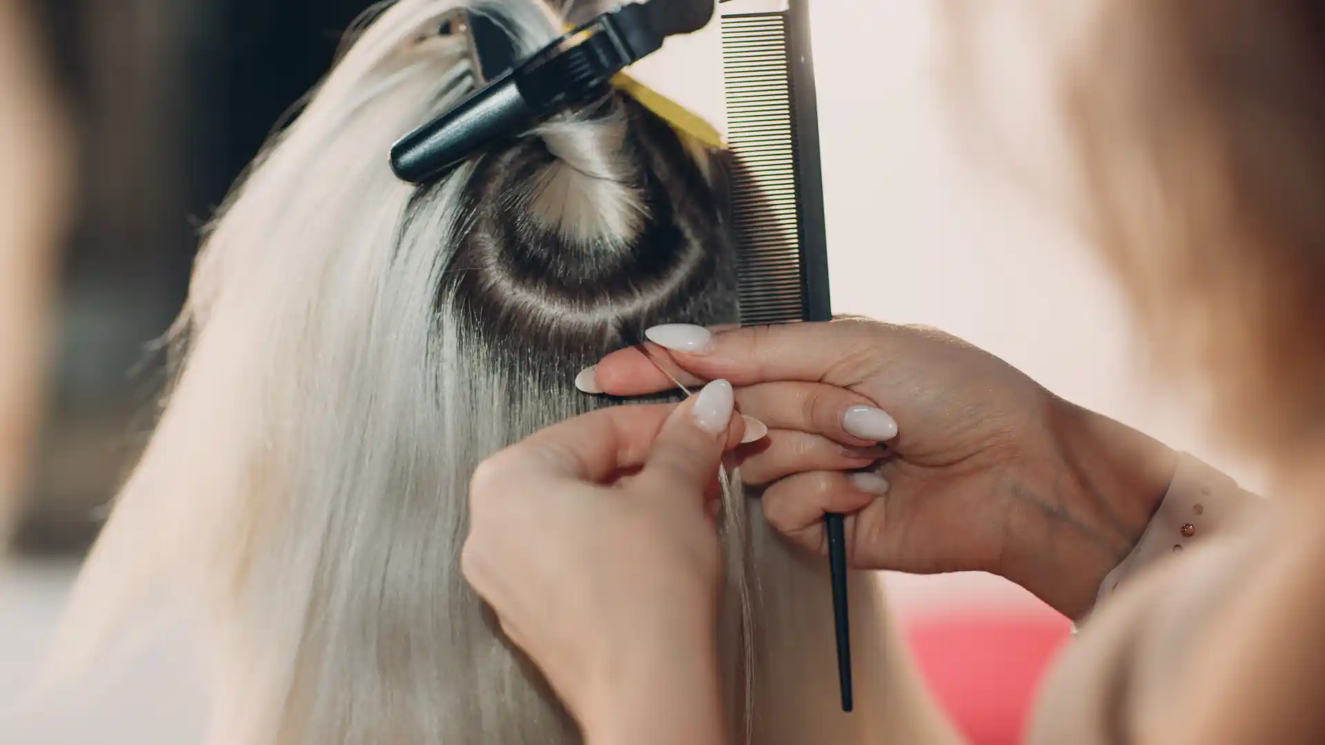 Hairdresser applying hair extensions to blonde hair using a clip-in method.