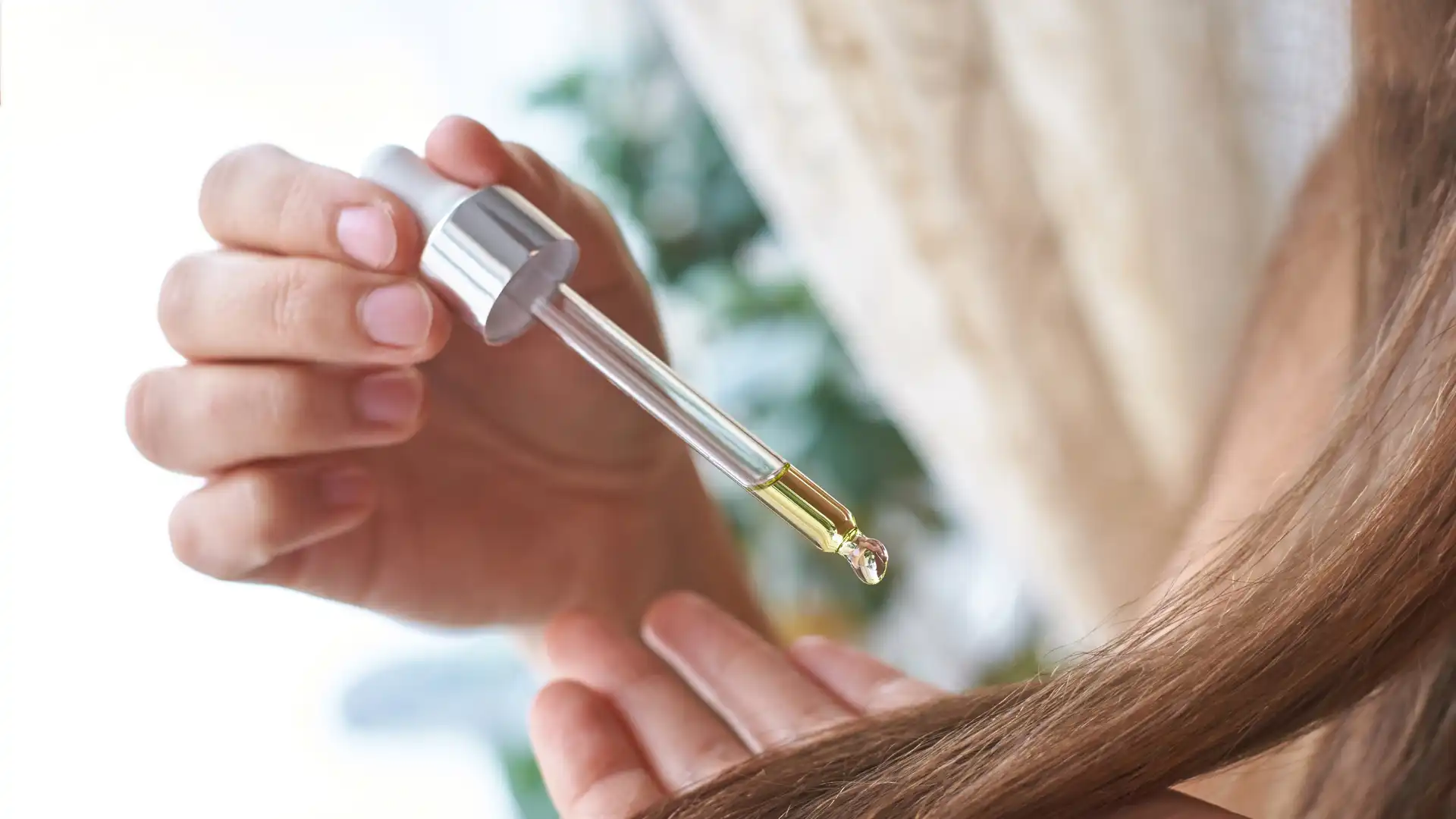 Applying hair oil with dropper onto scalp